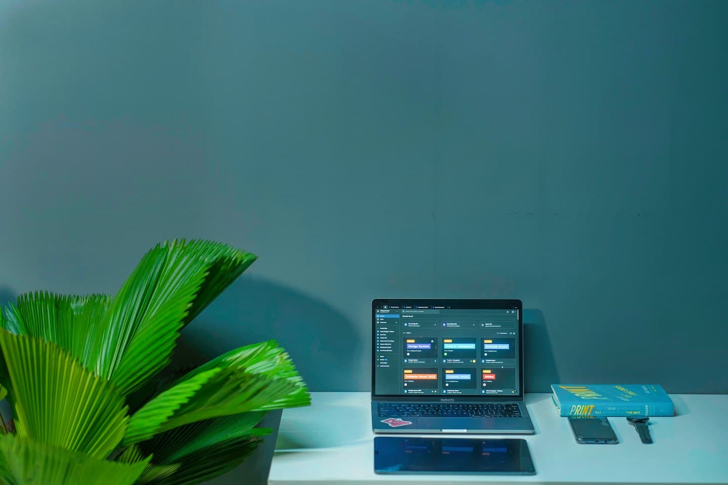 Laptop with project management software on a clean desk with a plant.